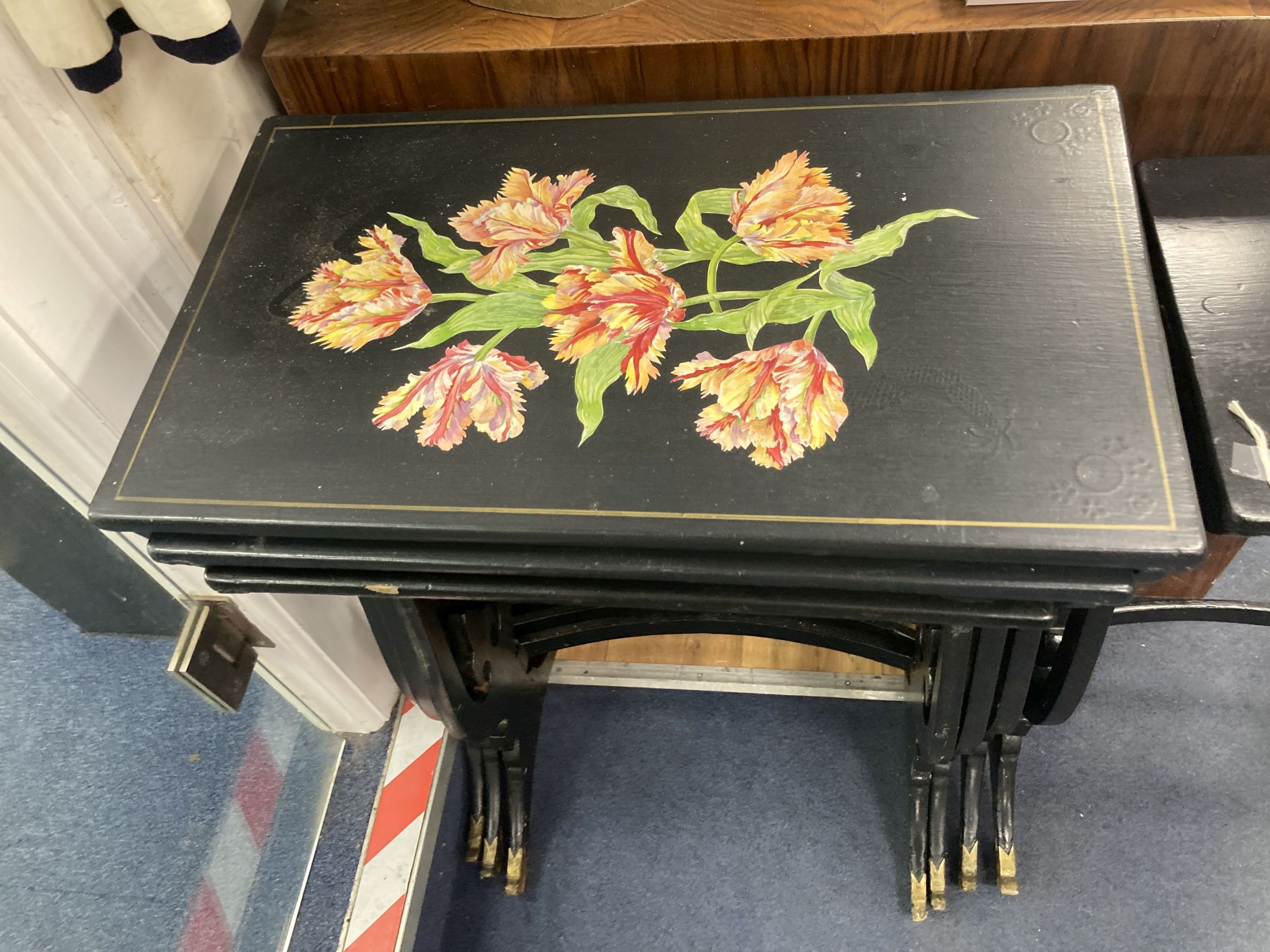 A graduating nest of four Regency style occasional tables with lyre shaped supports, black painted finish with gilt mask detail to supp